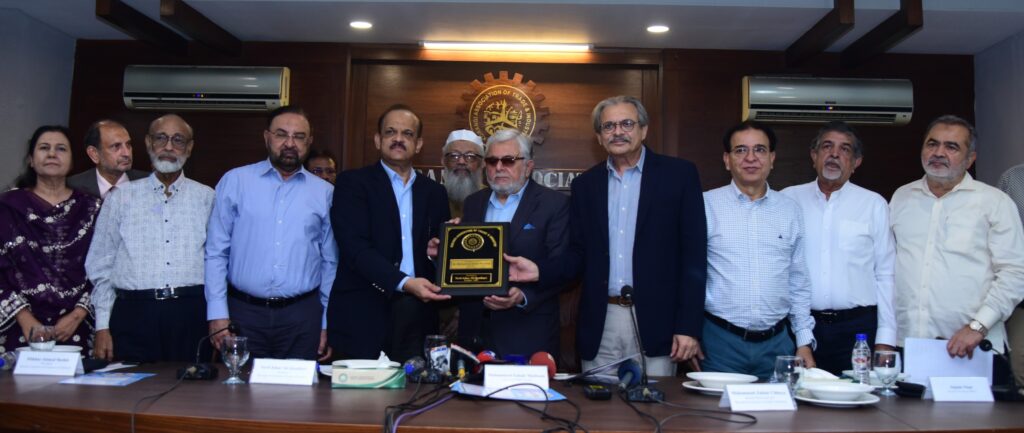 KATI President Johar Qandhari presents a shield to BMG Chairman Zubair Motiwala, joined by Zubair Chhaya, Nighat Awan, Muslim Mohammadi, Javed Balwani, Altaf Ghaffar, Masood Naqi, Anjum Nisar, and AQ Khalil.